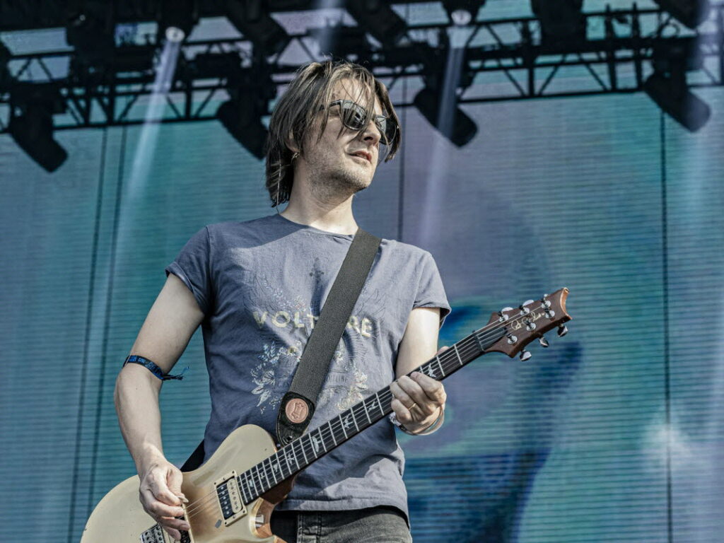 un compositeur avec une guitare sur scene