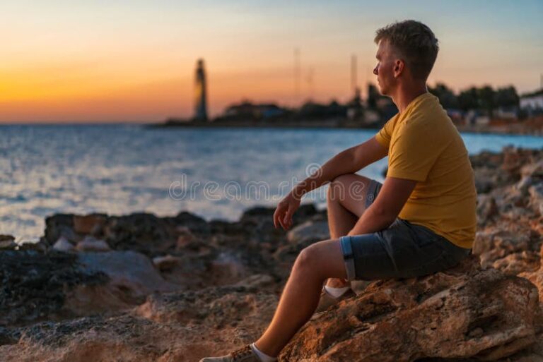 un homme pensif devant un coucher de soleil